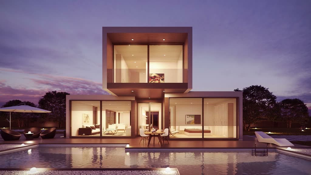 A glass-fronted house with a cantilevered upper storey, lit from within at dusk