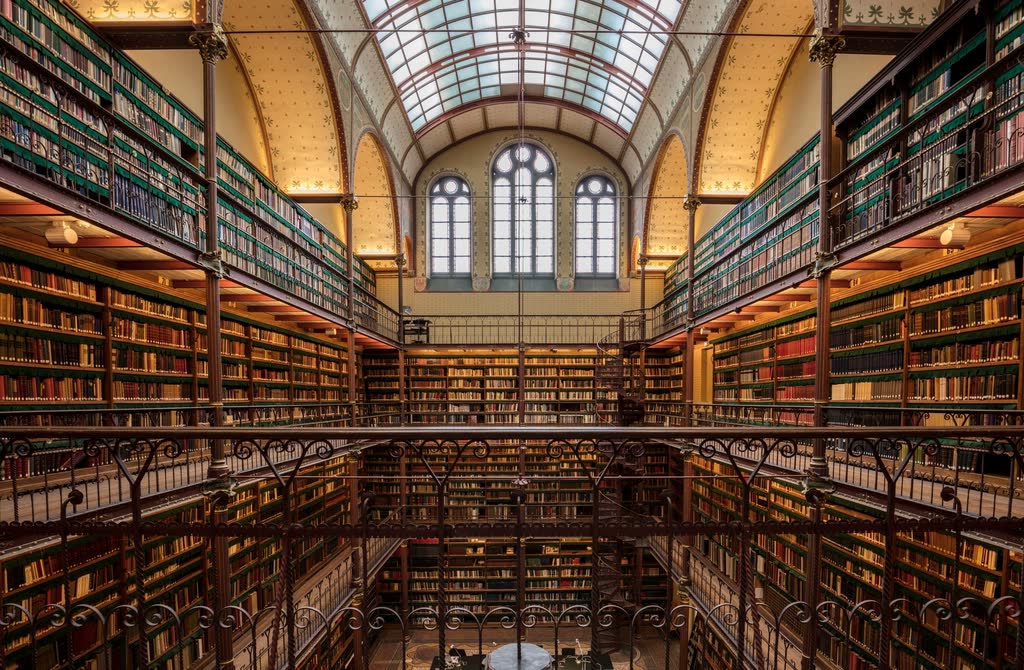 Archive of Light, plate 2: A double-height reading room with iron galleries and long shelves of books