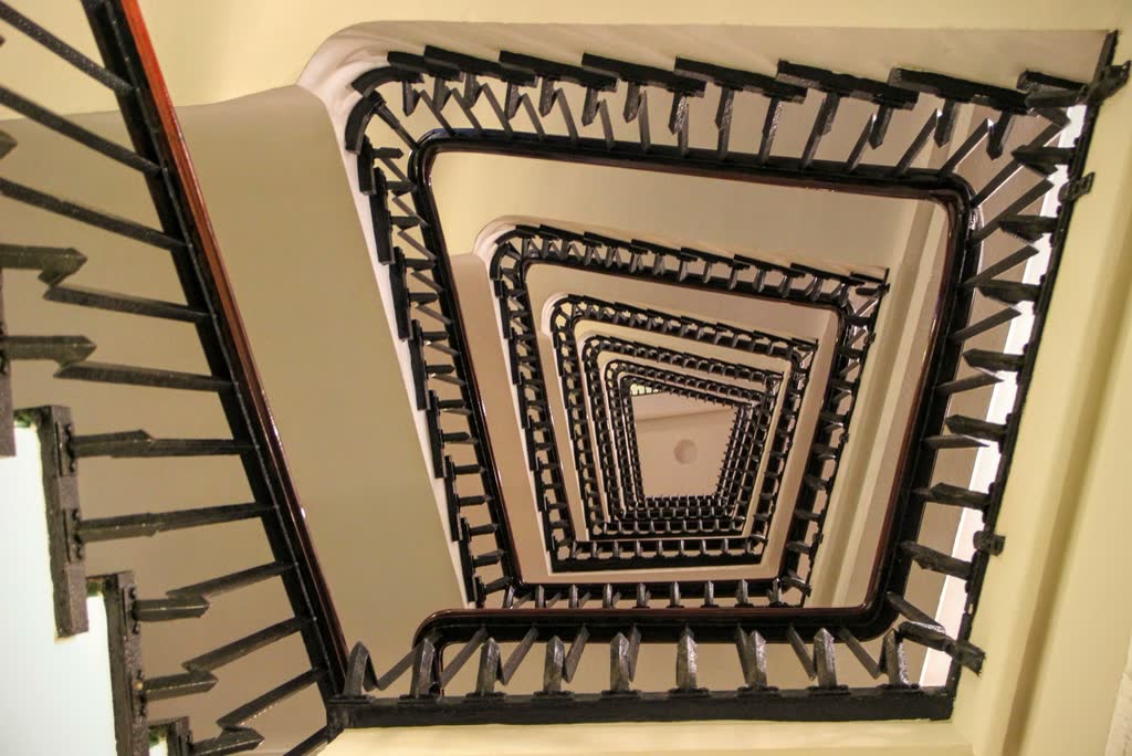 Ember Ryokan, plate 2: A stairwell seen from above, its square spiral of handrails receding downward